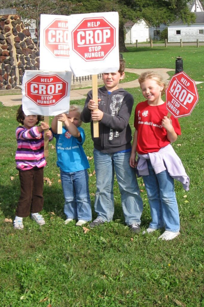 A group of kids holding signs in the grass.