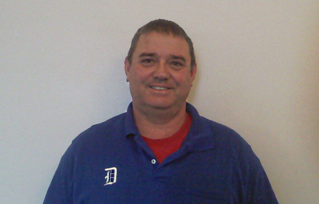 A man in blue shirt smiling for the camera.