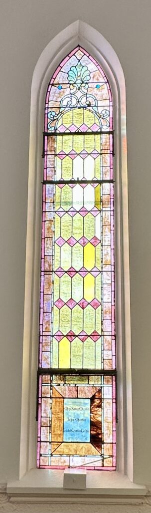 Tall arched stained glass window with geometric pattern