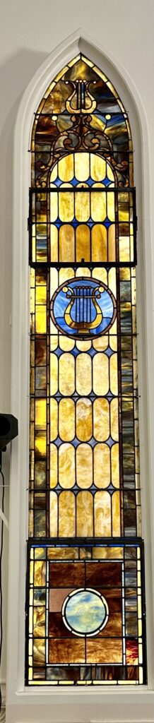 A stained glass window with a lyre in the center.
