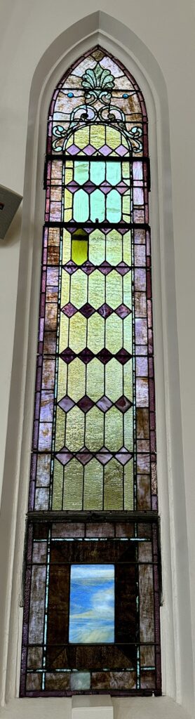 Narrow arched stained-glass window with sky panel
