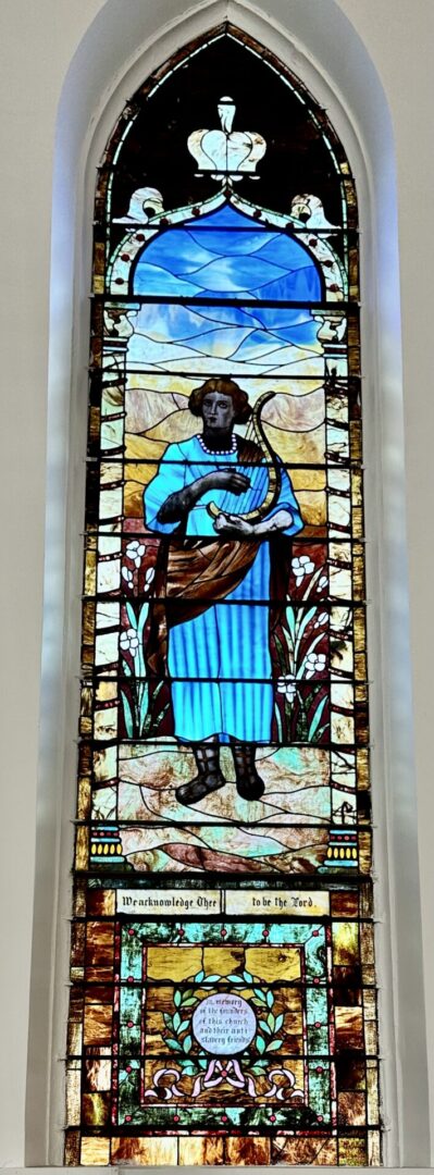 A stained glass window of a man holding a fish.