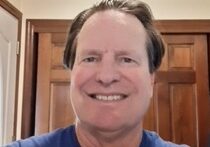 A man with long hair and a blue shirt