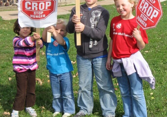A group of kids holding signs in the grass.