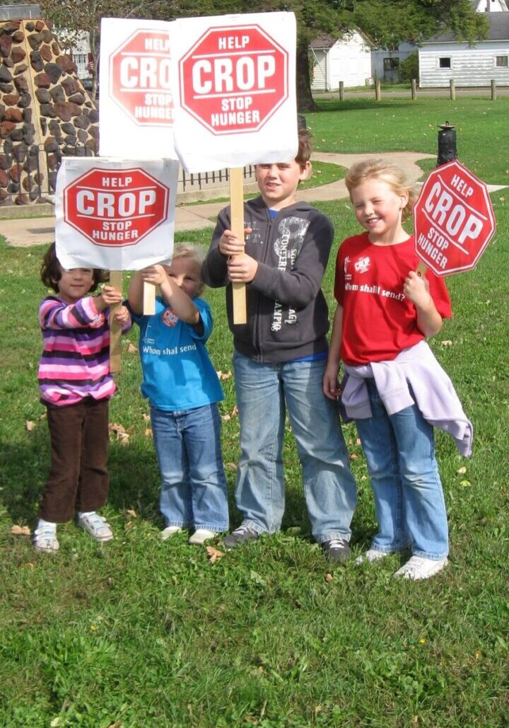 A group of kids holding signs in the grass.