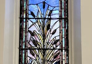 A stained glass window with a plant in the middle.