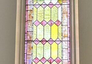 Tall arched stained glass window with geometric pattern