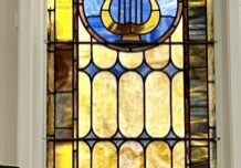 A stained glass window with a lyre in the center.