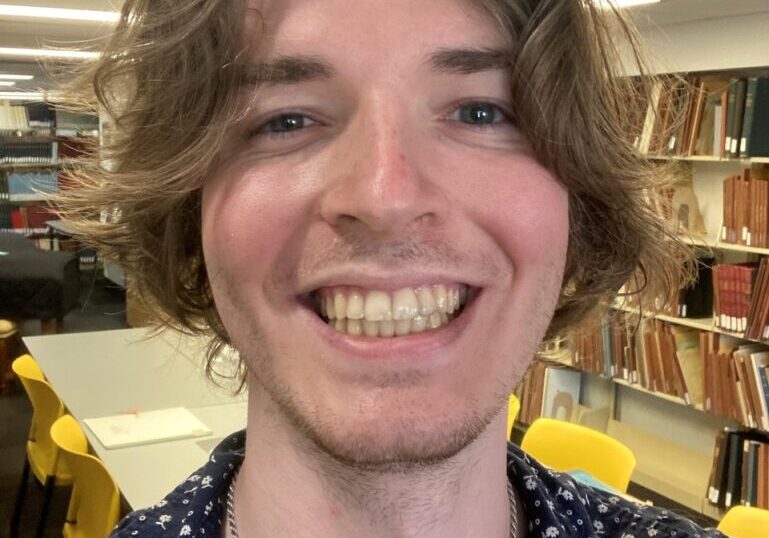 A man with long hair and a smile.