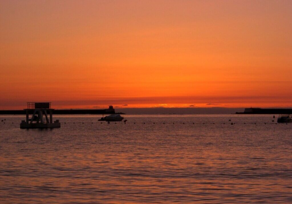 A boat is in the water at sunset.