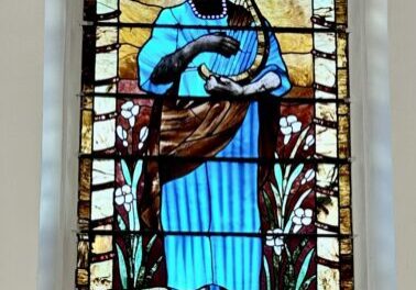 A stained glass window of a man holding a fish.