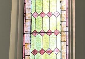 Arched stained-glass church window with floral motif